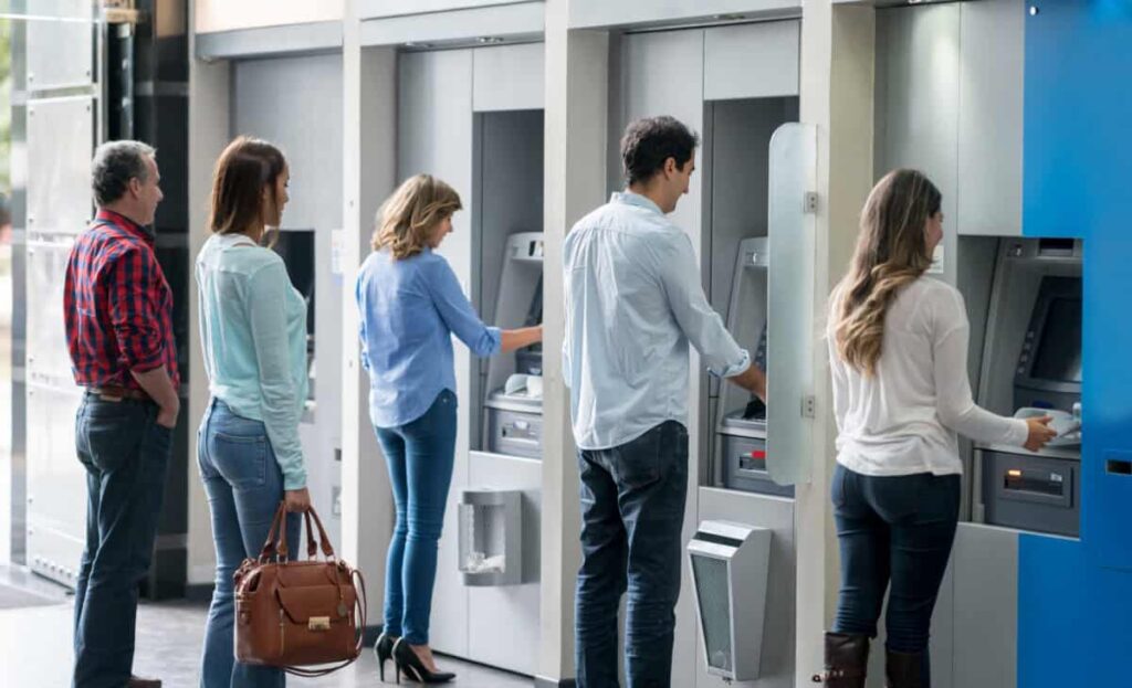 Canadian Bank Stocks in Late 2026: Which Ones I’d Buy and Which I’d Skip Group of people in a line at an ATM waiting to make a cash withdrawal